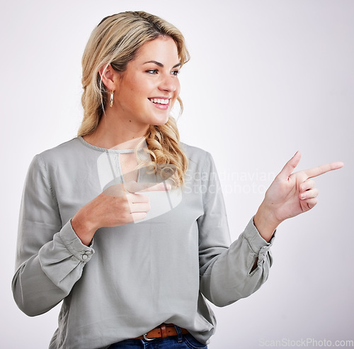 Image of Happy, woman and pointing to advertising at white background of offer, information and brand coming soon. Young female person, gesture and announcement of sales promotion, presentation and commercial