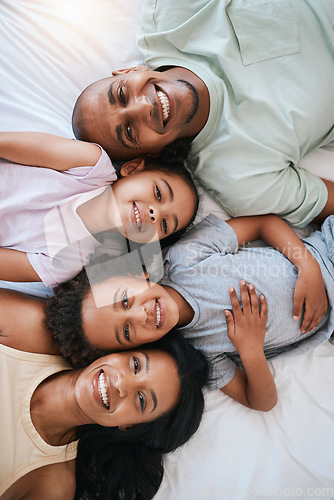 Image of Portrait, smile and top view of family in bedroom, bonding and relaxing together in home. Bed, happiness above and children with parents, face of mother and father enjoying quality time in house.