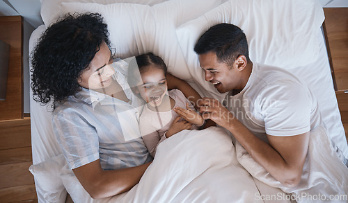 Image of Mom, dad and child tickle in a bedroom bed in the morning at family home with bonding. Laughing, mother and father with a young girl being playful and happy with a smile and youth together with love