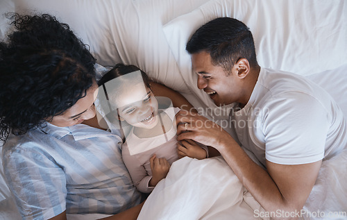 Image of Mom, dad and child laugh in a bedroom bed in the morning at family home with bonding. Tickle, mother and father with a young girl being playful and happy with a smile and youth together with love