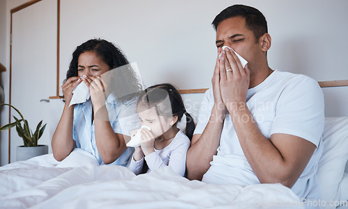 Image of Sick, family and blowing nose in bed in home lying in bedroom together in house. Flu, parents and child wipe with tissue with man, woman and girl with covid, virus or cold, disease or winter allergy