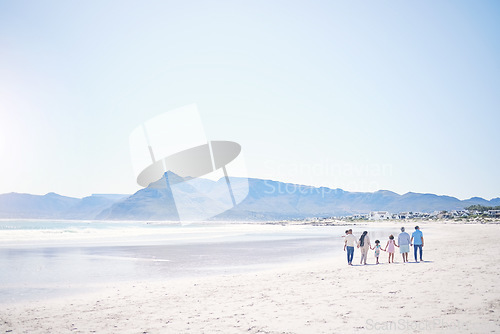 Image of Family, beach and holding hands with mockup space by blue sky, walking and bonding with love in summer holiday. Men, women and children for support, vacation and ocean mock up with waves in sunshine
