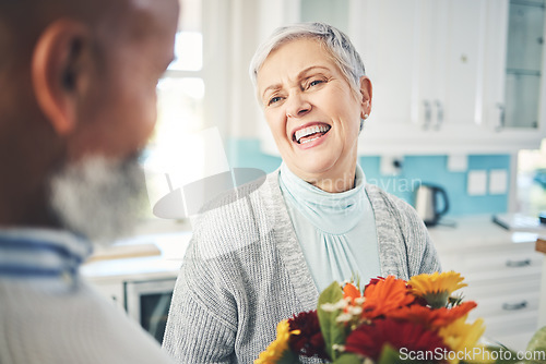 Image of Love, gift and senior couple with flowers, smile and loving at home, bonding and romance. Romantic, man and woman with floral present, celebrate anniversary and relationship with joy and quality time