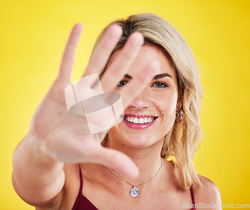 Image of Palm, frame and portrait of woman with hands on yellow background saying stop or no with body language and natural cosmetics. Beauty, happiness and face of happy person with confidence in studio