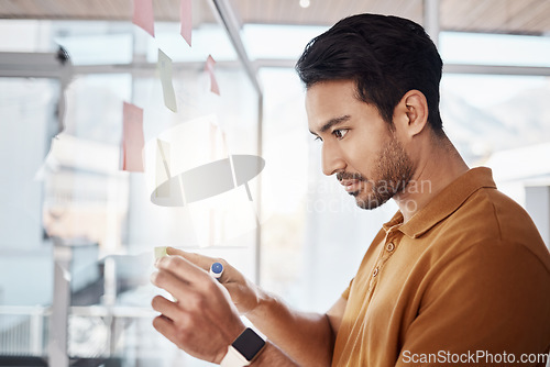 Image of Business man, sticky note and planning on glass board, writing and focus in startup workplace. Young businessman, moodboard and brainstorming with research, goals and ideas for solution in office