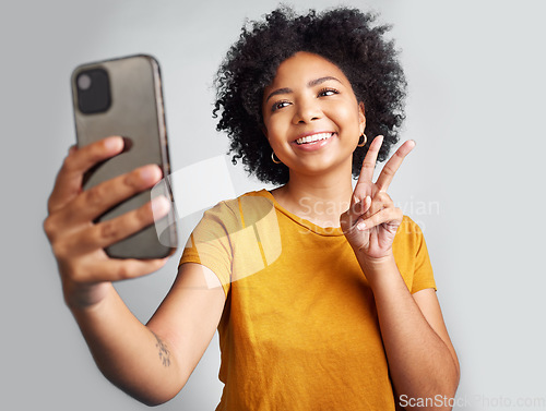 Image of Peace sign, selfie and smile with woman in studio for social media, connection and profile picture. Happy, emoji and technology with female on white background for online update, trendy and gen z