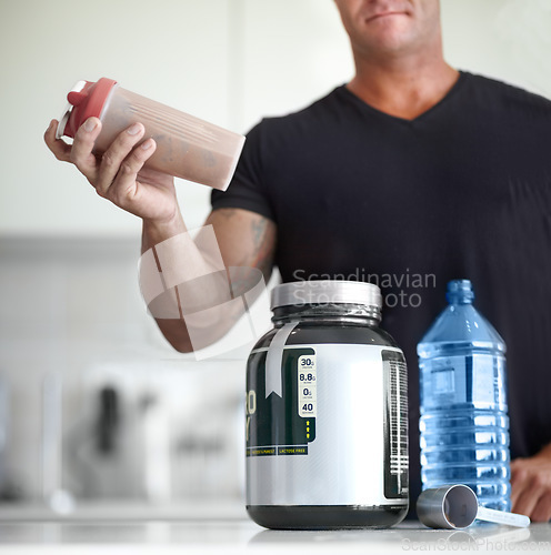 Image of Man, hands and protein shake for nutrition, muscle gain or body mass product and supplement on kitchen table. Hand of male bodybuilder preparing pre workout drink for exercise or healthy meal at home