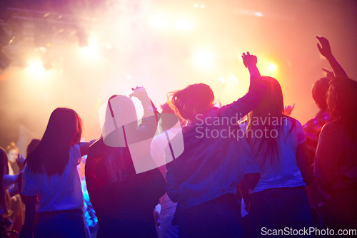 Image of Crowd, people dancing at concert or music festival from back, neon lights and energy at live event. Dance, fun and group of excited fans in arena at rock band performance or audience at rave party.