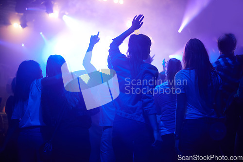 Image of Purple, neon light and people dancing at music festival from back, night and energy at live concert event. Dance, fun and group of excited fans in arena at rock band performance or crowd at party.