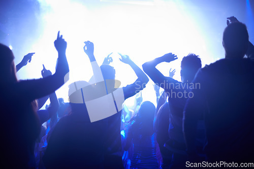 Image of Blue, neon lights and people dancing at music festival from back, lighting and energy at live concert event. Dance, fun and group of excited fans in arena at rock band performance or crowd at party.