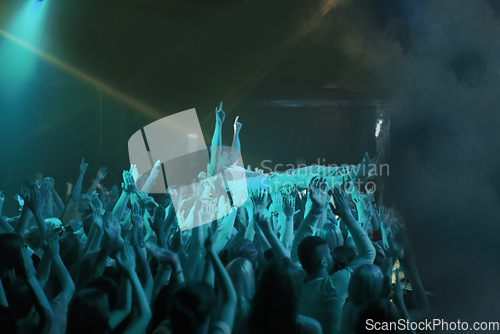 Image of Crowd surf, blue light and people at concert or at music festival, lights and energy at live event. Dance, fun and group of excited fans in arena at rock show performance, group carrying fan on hands