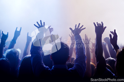 Image of Music, hands raised and people at concert or festival from back, lights and energy in crowd at live event. Dance, fun and group of excited fans in arena at rock band performance or audience at party.