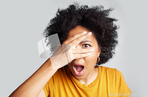 Image of Surprise, wow and woman peeking through hand isolated on a white background in studio. Shocked, face and African female person shy, embarrassed or fear, scared or shame, emoji or mind blown portrait.