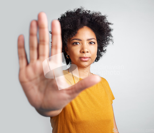 Image of Portrait, palm and warning with a woman in studio on a gray background for control or to stop abuse. Hand, protest and body language with an attractive young female person saying no in disagreement