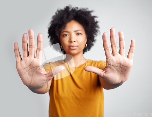 Image of Portrait, hands and warning with a woman in studio on a gray background for control or to stop abuse. Palm, protest and body language with an attractive young female person saying no in disagreement