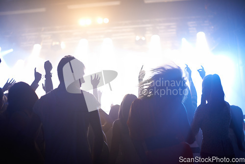 Image of Music, lighting and people at concert, dancing and energy at festival from back together at live event. Dance, fun and group of excited fans at stage arena or rock band performance and crowd at party