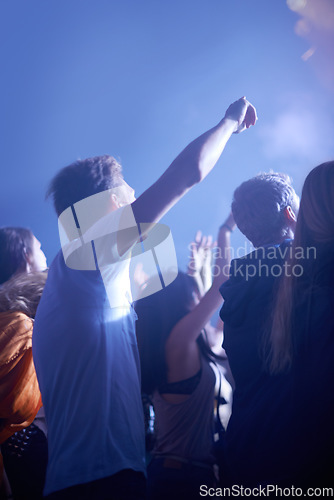 Image of Man in crowd, fans and dancing at concert, music festival and hands in air for energy or night event. Dance, fun or group of excited people in arena at rock band performance or audience rave party.