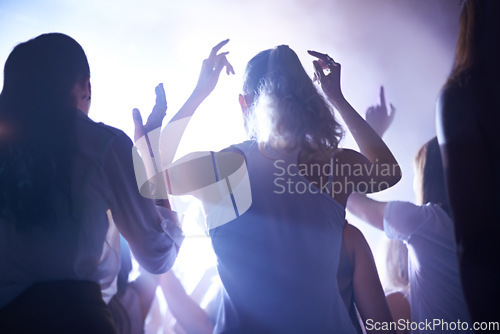 Image of Concert, music festival and women from back, lighting and energy in crowd at live night event. Dance, fun and group of excited fans in arena at rock band performance or audience at techno rave party.