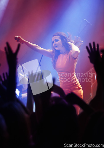 Image of People hands, singer woman and concert at night performance, singing and gen z in lights, celebration or cheers. Musician person on stage and microphone at event with fans, crowd or audience dancing