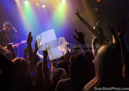 Image of Stage, lights and fans at rock concert or music festival, neon light and energy at live event. Dance, fun and purple lighting, group of excited people in arena at band performance or crowd at party.