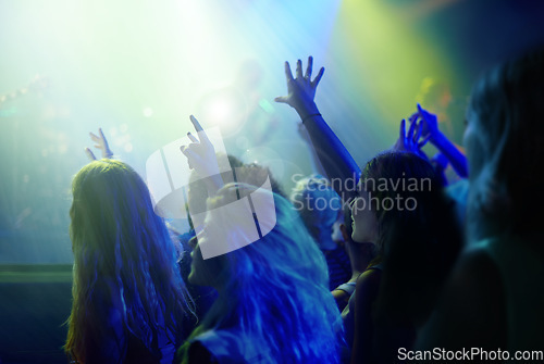 Image of Crowd, neon lights and people at concert or music festival dancing with energy and hands up at night event. Dance, fun and group of excited fans in arena at rock band performance or audience at party