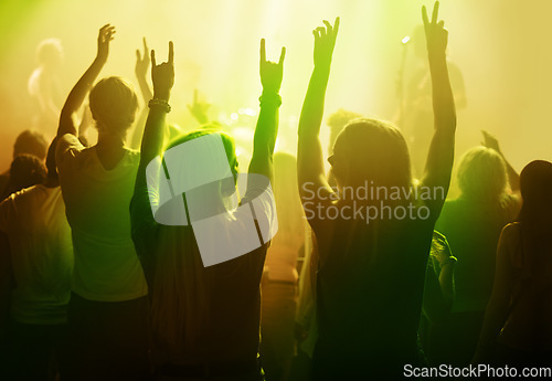 Image of Rock music, friends and women dancing at concert or festival from back, yellow neon light and energy at live event. Dance, fun and excited fans in arena at band performance or crowd at party together