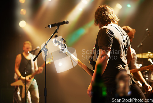 Image of Performance, musician and men in a band at a concert for a music festival, event or show together. Night, stage and a group of people performing, singing and playing instruments at a club for a party