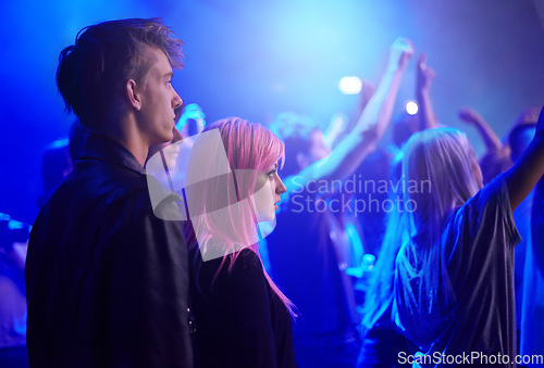 Image of Couple in crowd, man and woman at music festival, neon lights and watching live band performance on stage. Dance, group of people at party and blue lighting, fans on date at rock concert together.