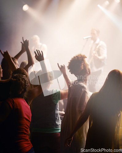 Image of People dancing, concert and singing music at night performance, gen z band singer with lights and cheers. Musician on stage at event and youth dance, crowd of fans or women audience with hands in air