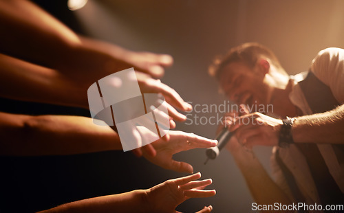 Image of Hands, fans at concert and musician at music festival with microphone on stage with front row crowd. Audience, excited people reach for singer and live band performance in arena with energy at show.