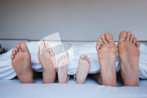 Image of Family feet, bed and home together with love, support and bonding in the morning. Sleep, bedroom and house with a mother, dad and child relax under a blanket with a foot from parents and kid