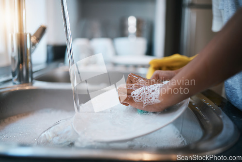 Image of Hands, sink and cleaning dishes with a person in the kitchen of a home to wash a plate for hygiene. Water, bacteria and soap with an adult washing porcelain crockery in a house to clean for housework