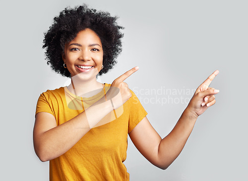 Image of Happy woman, portrait and pointing to advertising at white background, information offer and brand coming soon. Young female model gesture to sales announcement, commercial promotion and presentation