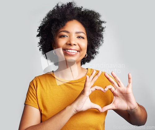 Image of Portrait, woman and smile with heart hands in studio, white background and care of kindness, emoji and icon. Happy young female model, love and finger shape for thank you, trust and hope of support