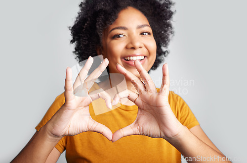 Image of Portrait of happy woman, heart and hand in studio, white background and care of kindness, emoji and icon. Young female model, love and finger shape with hands for thank you, trust and hope with smile