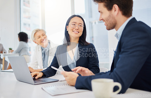 Image of Teamwork, young asian businesswoman on a laptop and talking to colleagues in an office. Happy diverse businesspeople, coordination or collaboration and planning for success with digital devices