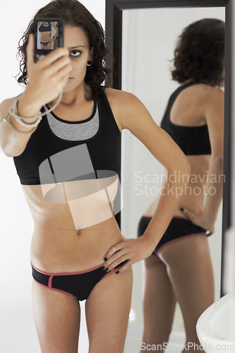 Image of Selfie, mental health and anorexia with a skinny woman by a mirror, posing for a photograph in her home. Phone, bulimia and eating disorder with a young female person suffering from depression