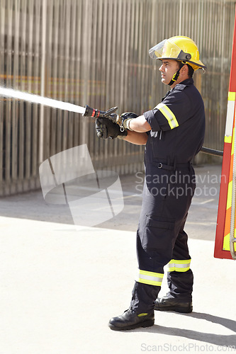Image of Male firefighter, spray water and emergency worker with helmet, uniform and brave to stop inferno. Fireman, fire hose and fearless on mission to rescue, health and safety service at job outdoor
