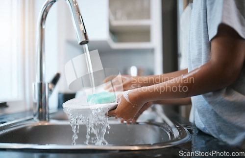 Image of Hands, sink and washing dishes with a person in the kitchen of a home to wash a plate for hygiene. Water, bacteria and soap with an adult cleaning porcelain crockery in a house to clean for housework