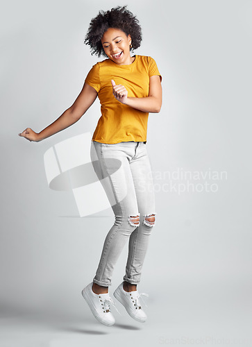 Image of Jump, excited and young woman celebrating success with smile or motion for freedom and happiness on grey studio background. Energy, winner and jumping for success or joy in the air for achievement