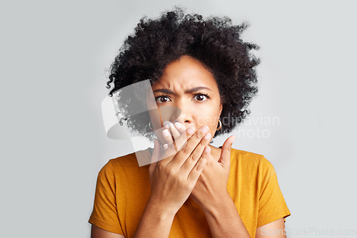 Image of Portrait, young woman and shocked with closed mouth or crossed hands and wide opened eyes on gray background. Face, fear and girl holding secret or astonished with bad news or information