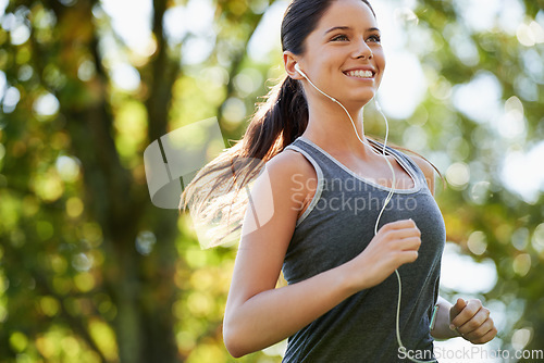 Image of Fitness, earphones and woman running in a park for health, wellness and outdoor exercise. Nature, sports and female athlete runner doing cardio workout in garden while listening to music and training