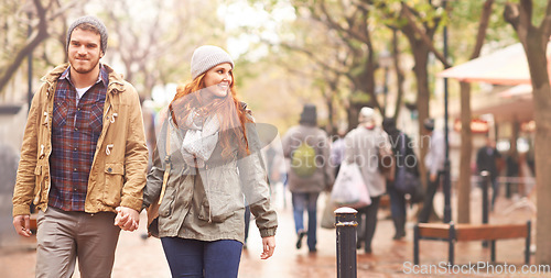 Image of Happy couple, holding hands and walking in city together in winter for romance or travel outdoors. Man and woman having a walk or stroll in park or town in happiness for romantic trip or traveling