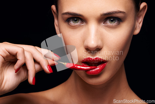 Image of Beauty, portrait and woman with a chilli in a studio for a sensual, glamour and sexy aesthetic. Cosmetic, makeup and female model with a pepper with red lipstick isolated by a dark black background.