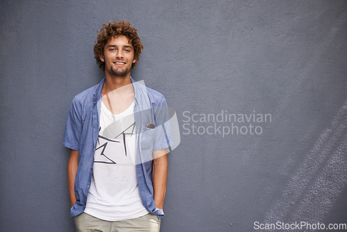 Image of Happy, smile and portrait of a man by a wall with mockup space with a casual, cool and stylish outfit. Happiness, positive and handsome male model with trendy style or fashion with gray background.
