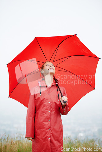 Image of Rain, happy and red umbrella with woman in nature for winter, storm and carefree. Happiness, weather and cold with female wearing raincoat in outdoor for waterproof, cloudy and protection