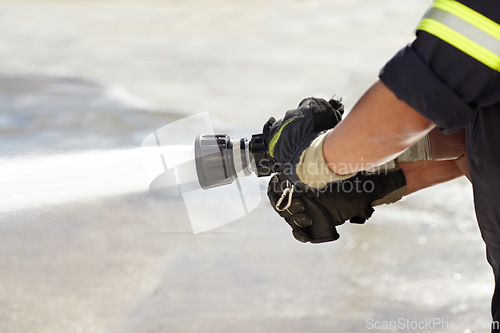 Image of Hands, spray and nozzle for water, firefighter and help in emergency, brave or stop inferno in uniform. Fireman, fire hose and fearless on mission to rescue, health and safety service at job outdoor