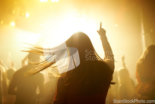 Image of Dance, music and back of woman at a concert, disco event or psychedelic trance festival. Night, energy and female person dancing or moving to a song with a yellow light at techno night club or party.