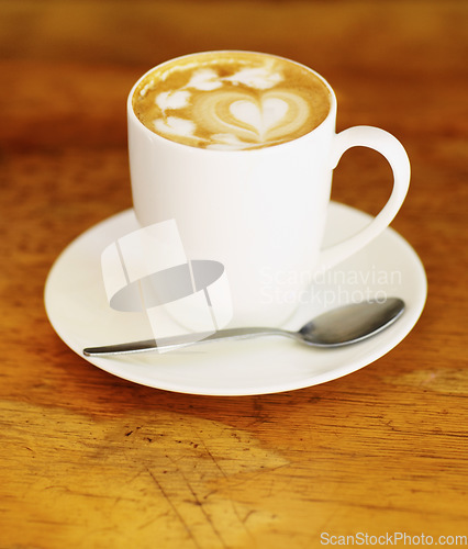 Image of Latte art, coffee and drink on table in cafe, closeup of hot beverage and artistic heart design with milk foam. Cappuccino, espresso and creative pattern on caffeine liquid brew in a cup on a plate