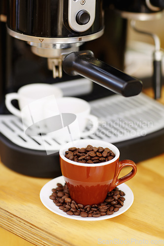 Image of Coffee beans, cups and machine on table in cafe for cappuccino, latte or hot drink. Restaurant, electrical appliance and caffeine mugs for making or brewing espresso in retail shop or small business.